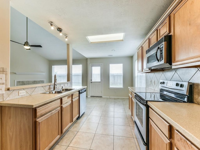 24247 Silversmith Ln, Katy, TX 77493 - kitchen with appliances with stainless steel finishes, a sink, decorative backsplash, light tile patterned flooring, and light countertops