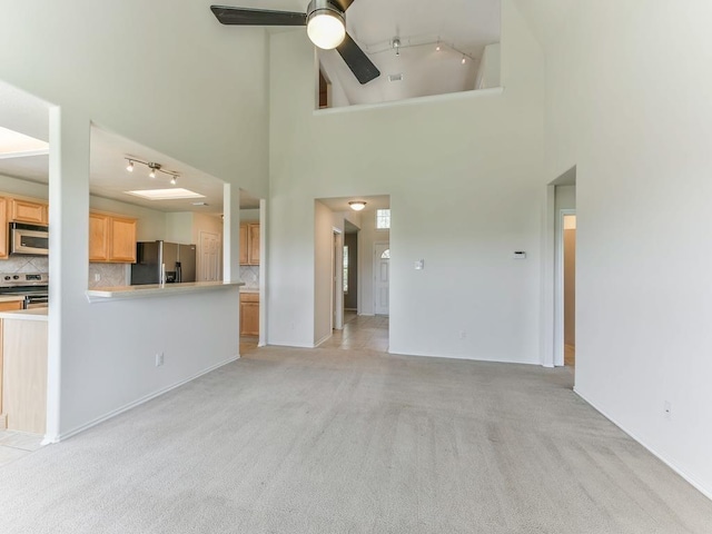 24247 Silversmith Ln, Katy, TX 77493 - unfurnished living room with track lighting, ceiling fan, light carpet, a towering ceiling, and baseboards