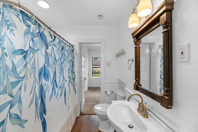 512 Gale St, Houston, TX 77009 - bathroom featuring a sink, toilet, wood finished floors, a wainscoted wall, and a shower with shower curtain