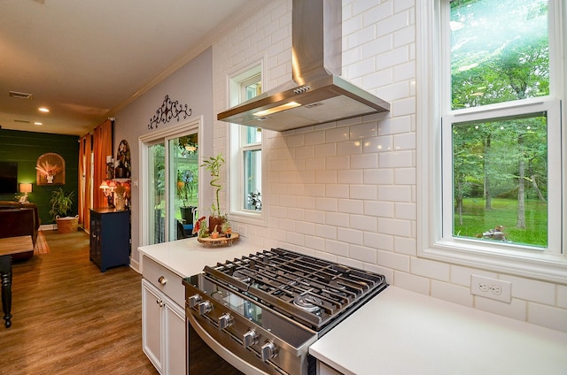 25292 Willow Creek Rd, Hockley, TX 77447 - kitchen with wall chimney range hood, stainless steel range with gas cooktop, crown molding, decorative backsplash, and light countertops