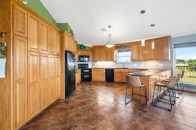 1504 W Saint Louis Ave, Seadrift, TX 77983 - kitchen with black appliances, a breakfast bar area, a peninsula, tasteful backsplash, and decorative light fixtures