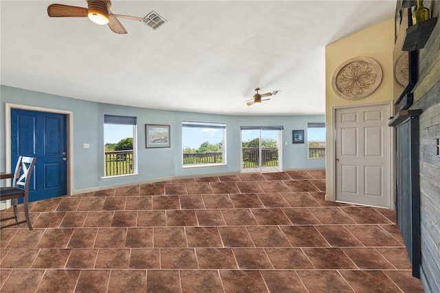 1504 W Saint Louis Ave, Seadrift, TX 77983 - unfurnished living room featuring ceiling fan, healthy amount of natural light, and dark tile patterned floors
