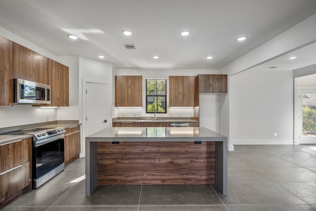 10728 Twin Oak Dr, Conroe, TX 77385 - kitchen featuring appliances with stainless steel finishes, modern cabinets, brown cabinetry, and recessed lighting