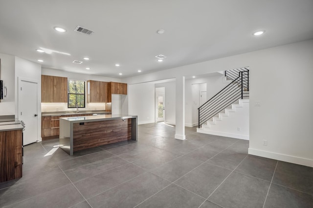 10728 Twin Oak Dr, Conroe, TX 77385 - kitchen featuring recessed lighting, a center island, brown cabinets, dark tile patterned flooring, and modern cabinets