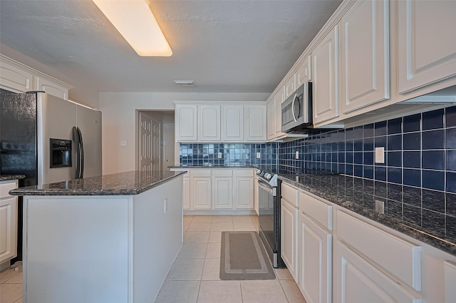 3619 Strartford Arms Ln, Sugar Land, TX 77498 - kitchen with stainless steel appliances, light tile patterned flooring, a center island, decorative backsplash, and white cabinetry