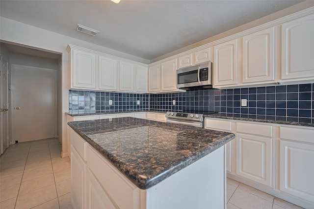 3619 Strartford Arms Ln, Sugar Land, TX 77498 - kitchen featuring stainless steel appliances, light tile patterned floors, white cabinetry, decorative backsplash, and dark stone counters