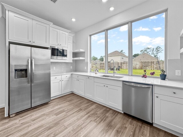 4326 Camden Springs Trl, Porter, TX 77365 - kitchen featuring stainless steel appliances, a sink, white cabinets, light wood finished floors, and light countertops