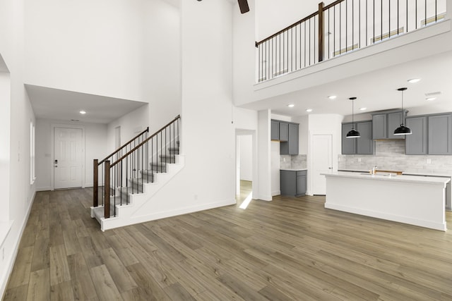 4826 Sand Clouds, Katy, TX 77493 - unfurnished living room with a towering ceiling, wood finished floors, a ceiling fan, stairs, and a sink
