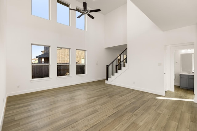 4826 Sand Clouds, Katy, TX 77493 - unfurnished living room featuring a ceiling fan, light wood-style flooring, stairway, baseboards, and a towering ceiling