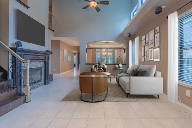 23 N Plum Crest Cir, The Woodlands, TX 77382 - living area featuring a ceiling fan, a high ceiling, a tiled fireplace, tile patterned floors, and baseboards