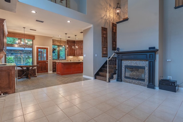 23 N Plum Crest Cir, The Woodlands, TX 77382 - living room featuring a chandelier, stairway, light tile patterned floors, a towering ceiling, and a tile fireplace