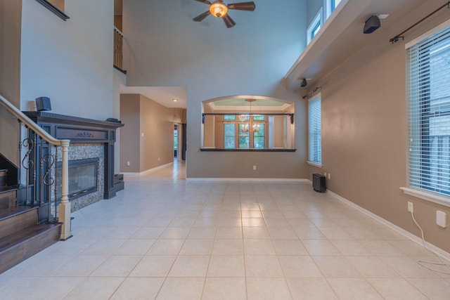 23 N Plum Crest Cir, The Woodlands, TX 77382 - unfurnished living room featuring a ceiling fan, a high ceiling, baseboards, a tiled fireplace, and tile patterned floors