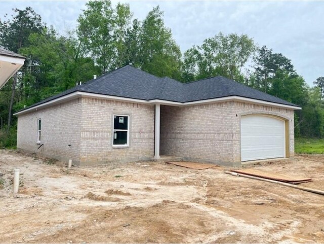 10730 Vinson St, Beaumont, TX 77713 - view of front of home featuring brick siding, an attached garage, view of scattered trees, and driveway