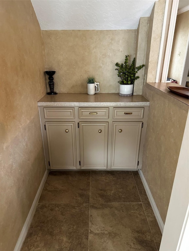 detailed view of baseboards and a textured wall