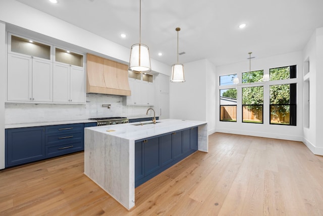 1032 W 41st St, Houston, TX 77018 - kitchen with a sink, custom exhaust hood, blue cabinetry, backsplash, and light stone counters