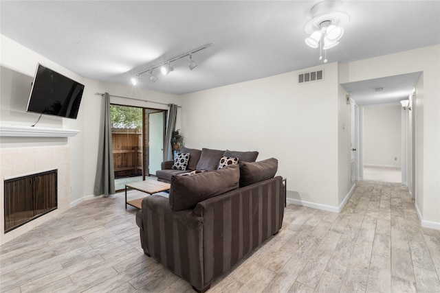 2601 S Braeswood Blvd S Unit 1403, Houston, TX 77025 - living area featuring light wood-style flooring, track lighting, a tiled fireplace, and baseboards
