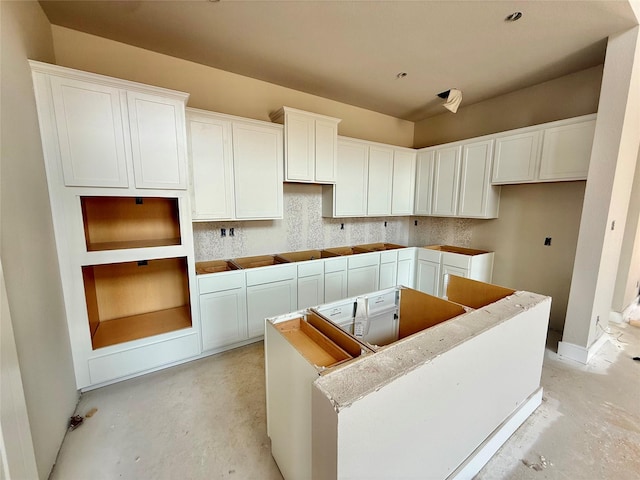 24538 Greeley Lake Dr, Katy, TX 77493 - kitchen featuring a center island, concrete floors, white cabinetry, and baseboards