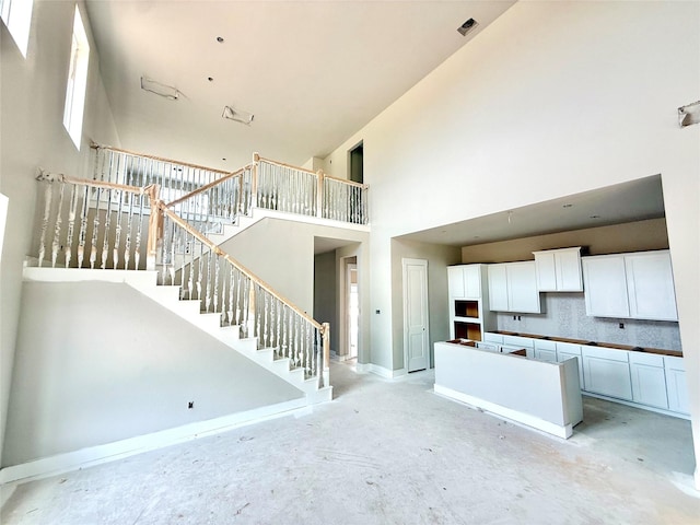 24538 Greeley Lake Dr, Katy, TX 77493 - unfurnished living room with a towering ceiling, stairway, and baseboards