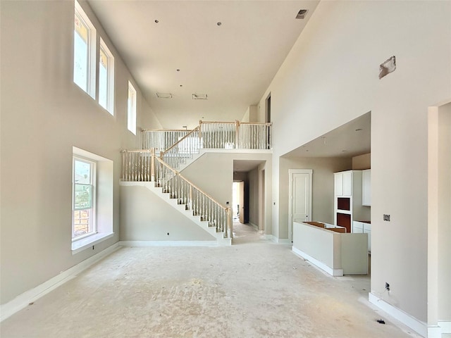 24538 Greeley Lake Dr, Katy, TX 77493 - unfurnished living room with a towering ceiling, plenty of natural light, stairs, and baseboards