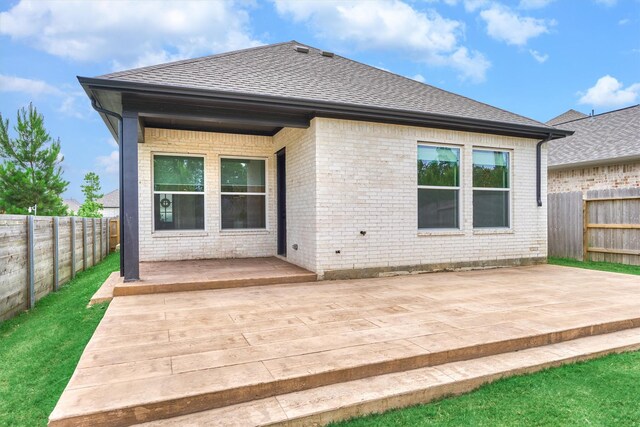 15611 Red Panda Rd, Conroe, TX 77302 - back of property featuring a fenced backyard, brick siding, roof with shingles, a patio area, and a deck