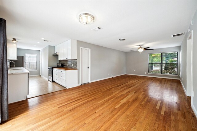 2009 Sedgie Dr, Houston, TX 77080 - unfurnished living room featuring light wood-style flooring, ceiling fan, baseboards, and a sink