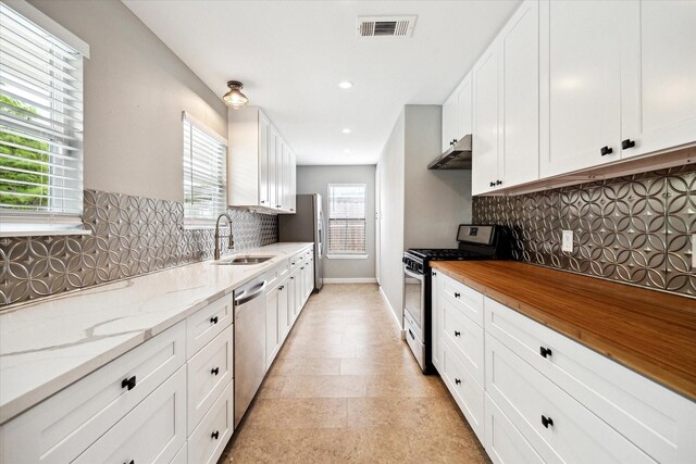 2009 Sedgie Dr, Houston, TX 77080 - kitchen featuring appliances with stainless steel finishes, a sink, under cabinet range hood, white cabinetry, and recessed lighting