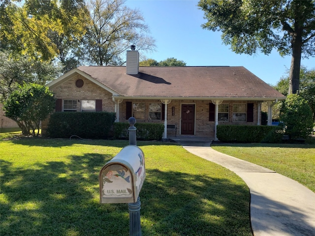 12595 Sagittarius Dr E, Willis, TX 77318 - view of front facade with brick siding, a front yard, a chimney, and covered porch