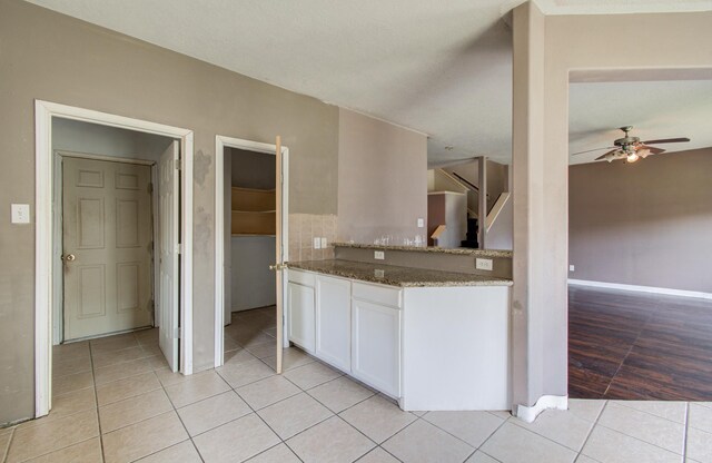 1418 High Thicket Ct, Spring, TX 77373 - kitchen with ceiling fan, light tile patterned floors, white cabinetry, stone countertops, and baseboards
