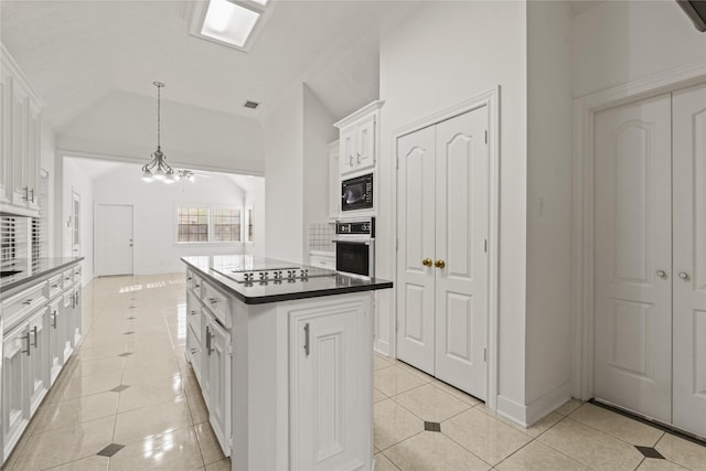 1015 Flagmore Dr, Katy, TX 77450 - kitchen with black microwave, light tile patterned flooring, white cabinets, dark countertops, and lofted ceiling
