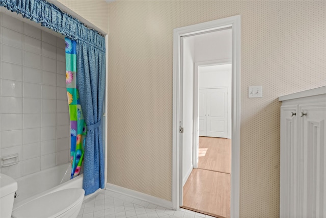 1015 Flagmore Dr, Katy, TX 77450 - bathroom with toilet, tile patterned flooring, baseboards, wallpapered walls, and shower / bath combo with shower curtain