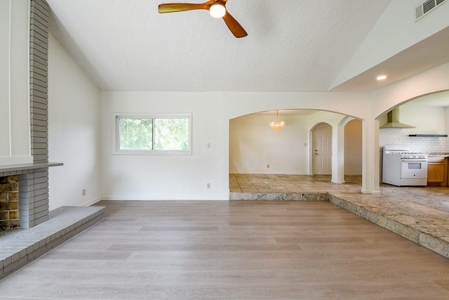 406 Shadylawn St, Shoreacres, TX 77571 - unfurnished living room with lofted ceiling, arched walkways, ceiling fan, a textured ceiling, and light wood finished floors
