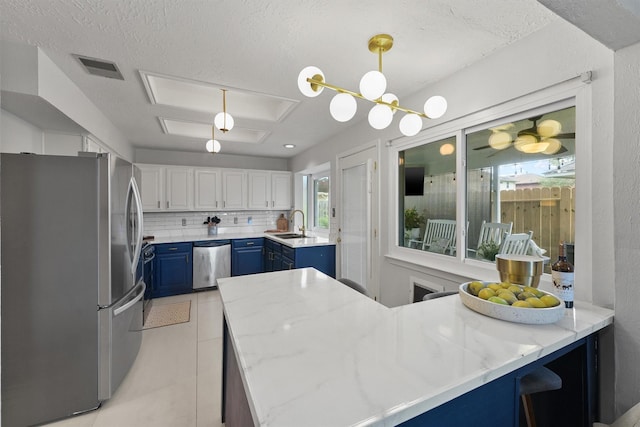 8515 Cold Lake Dr, Houston, TX 77088 - kitchen featuring appliances with stainless steel finishes, blue cabinetry, a peninsula, a sink, and backsplash