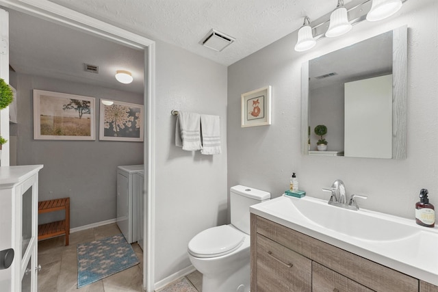 8515 Cold Lake Dr, Houston, TX 77088 - bathroom with washer and dryer, toilet, vanity, tile patterned floors, and a textured ceiling