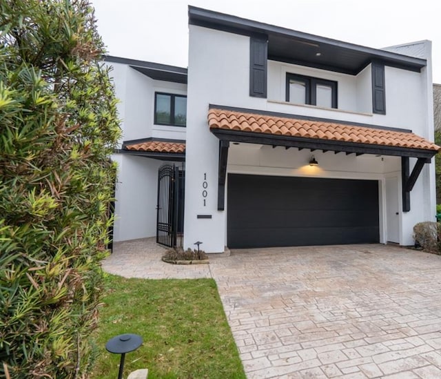 1001 Potomac Dr, Houston, TX 77057 - view of front of house with a garage, stucco siding, decorative driveway, and a tiled roof