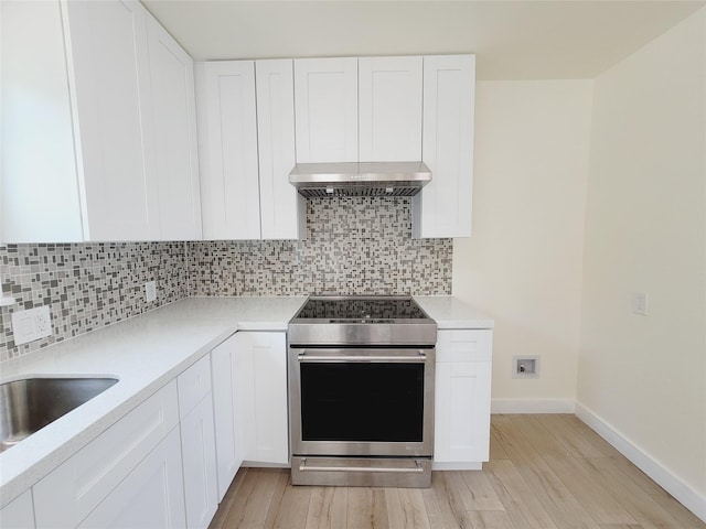 9926 Tangiers Rd, Houston, TX 77041 - kitchen featuring stainless steel electric range, under cabinet range hood, light wood-style floors, decorative backsplash, and light countertops
