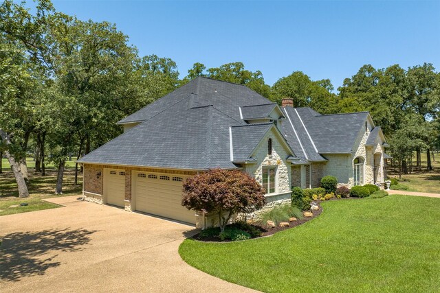 167 Saint Andrews Dr E, Mabank, TX 75156 - view of home's exterior featuring stone siding, roof with shingles, a yard, a garage, and driveway