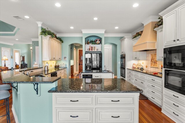 167 Saint Andrews Dr E, Mabank, TX 75156 - kitchen with arched walkways, a sink, black appliances, custom range hood, and dark stone countertops