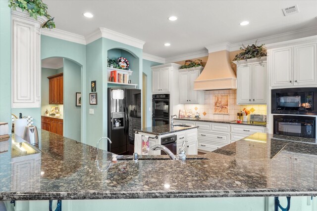 167 Saint Andrews Dr E, Mabank, TX 75156 - kitchen featuring black appliances, custom range hood, dark stone countertops, crown molding, and backsplash