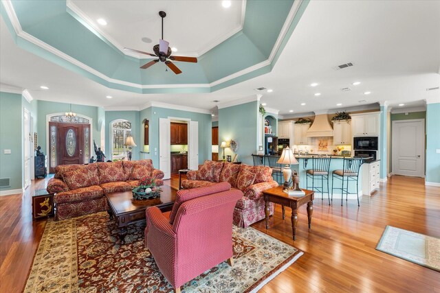 167 Saint Andrews Dr E, Mabank, TX 75156 - living area featuring crown molding, a ceiling fan, a chandelier, light wood-style floors, and a tray ceiling