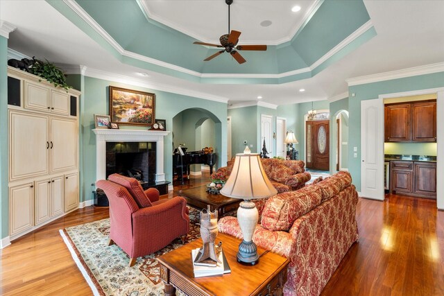 167 Saint Andrews Dr E, Mabank, TX 75156 - living area with arched walkways, a tile fireplace, light wood-style flooring, ceiling fan, and ornamental molding