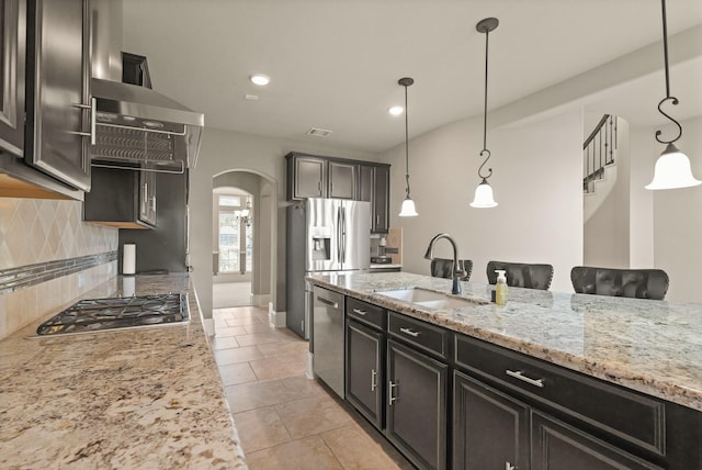 17006 Shannon Lake Ct, Houston, TX 77044 - kitchen featuring a sink, arched walkways, appliances with stainless steel finishes, decorative backsplash, and pendant lighting
