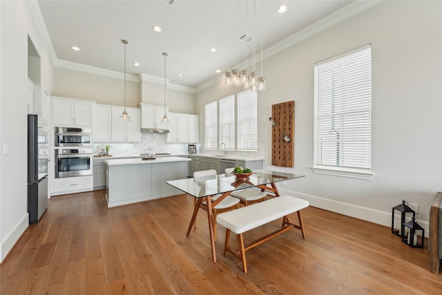 10756 Craighead Dr, Houston, TX 77025 - kitchen with stainless steel appliances, a center island, backsplash, light countertops, and crown molding