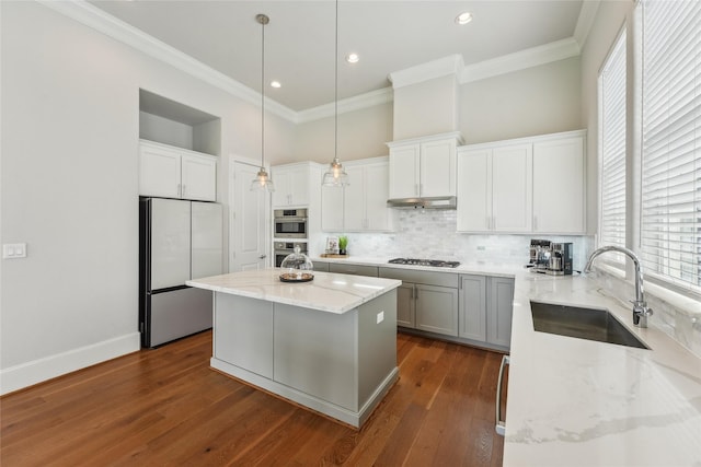 10756 Craighead Dr, Houston, TX 77025 - kitchen featuring appliances with stainless steel finishes, a sink, tasteful backsplash, light stone counters, and a kitchen island