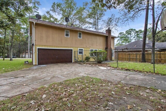 2102 Silver Moon Trl, Crosby, TX 77532 - back of property with a chimney, concrete driveway, and an attached garage