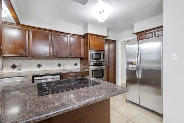 2102 Silver Moon Trl, Crosby, TX 77532 - kitchen featuring stainless steel appliances, decorative backsplash, light tile patterned floors, dark stone countertops, and dark brown cabinetry