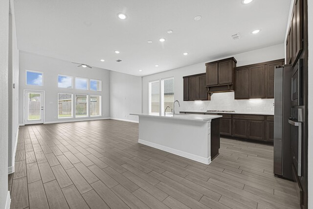 24634 Carleton Lake Ln, Tomball, TX 77375 - kitchen featuring a sink, decorative backsplash, baseboards, light countertops, and light wood-style flooring
