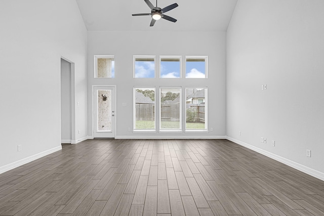 24634 Carleton Lake Ln, Tomball, TX 77375 - unfurnished living room with high vaulted ceiling, a ceiling fan, dark wood-type flooring, and baseboards