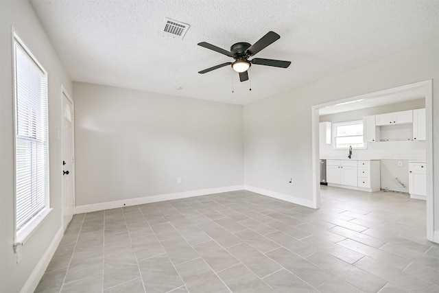 5007 Northridge Dr, Houston, TX 77033 - unfurnished room with a ceiling fan, a textured ceiling, a sink, baseboards, and light tile patterned flooring