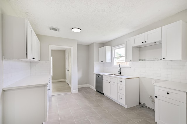 5007 Northridge Dr, Houston, TX 77033 - kitchen with stainless steel dishwasher, a sink, tasteful backsplash, white cabinets, and a textured ceiling