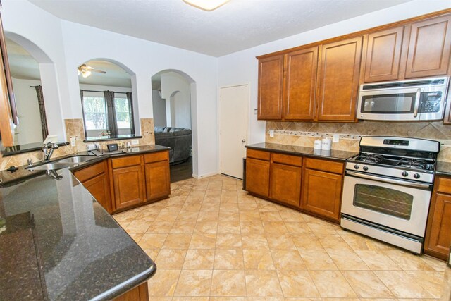 15102 Dry Ridge Ct, Humble, TX 77346 - kitchen with stainless steel appliances, a sink, backsplash, and brown cabinets